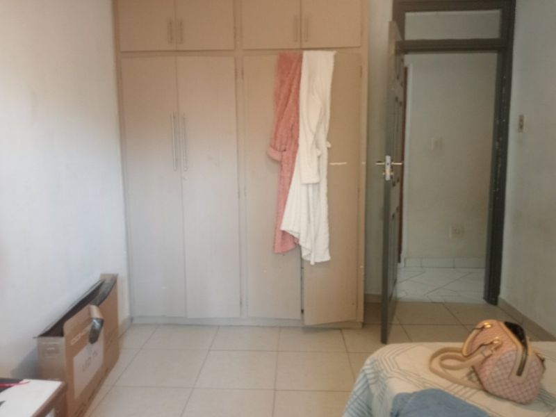 A bedroom featuring built-in cupboards and tiled flooring, providing functional storage space with potential for cosmetic updates.