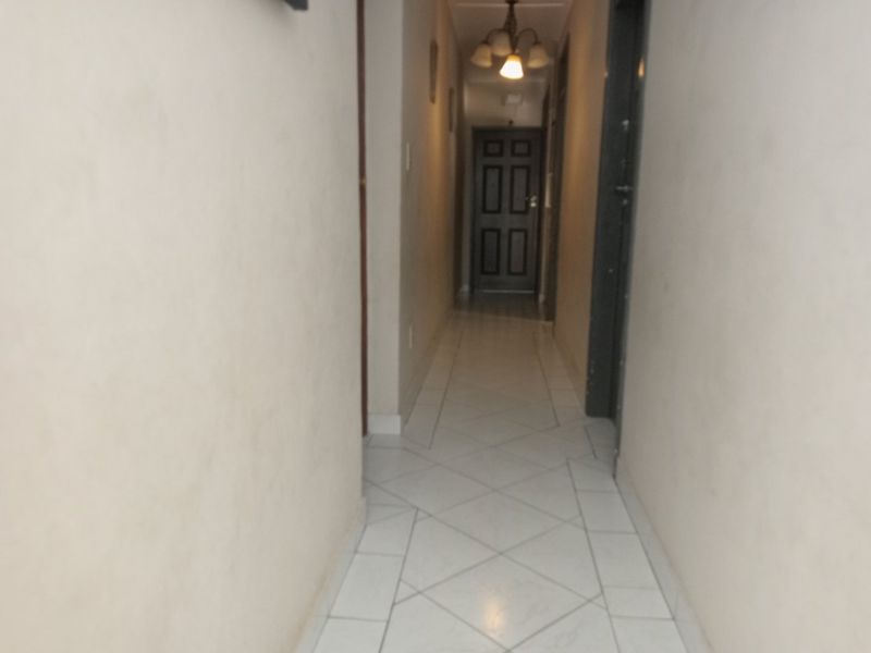 A simple, tiled hallway providing access to various rooms within the home, featuring neutral walls and a central ceiling light fixture.
