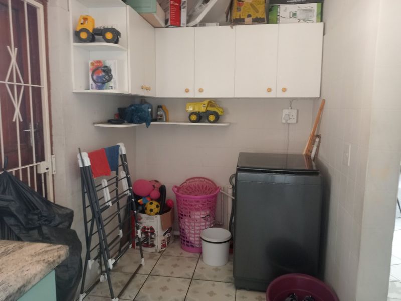 A functional laundry area featuring built-in overhead cabinetry and tiled flooring, providing practical utility space for household tasks.