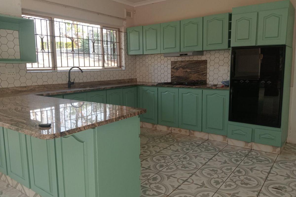 Spacious kitchen featuring granite countertops, built-in oven, hob, extractor fan, and ample cabinetry, offering a functional layout ready for modern updates.