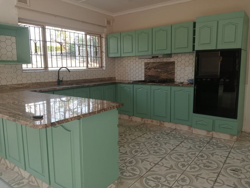 Spacious kitchen featuring granite countertops, built-in oven, hob, extractor fan, and ample cabinetry, offering a functional layout ready for modern updates.