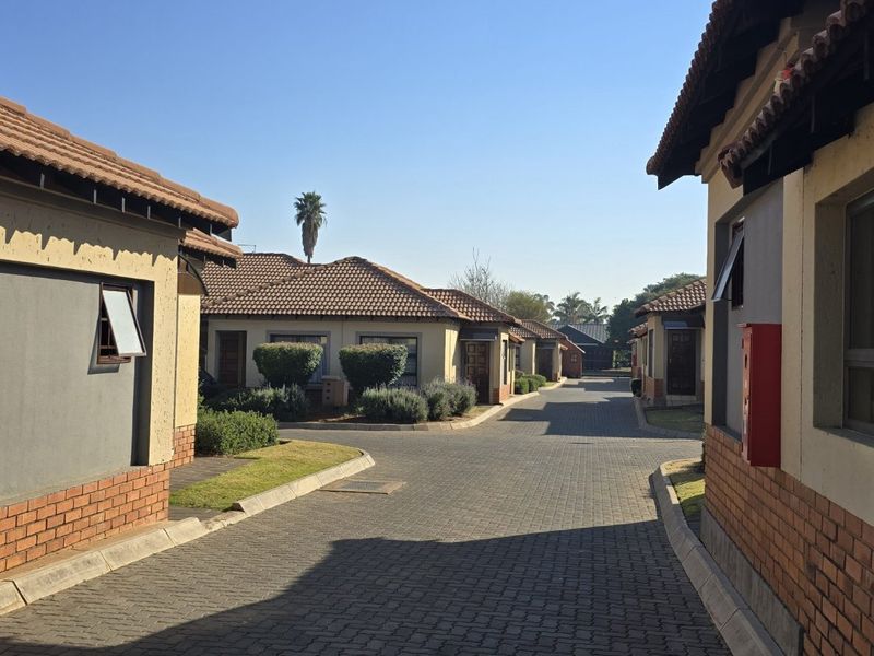A view of the complex driveway showing multiple townhouse units with tiled roofs and brick-accented facades.