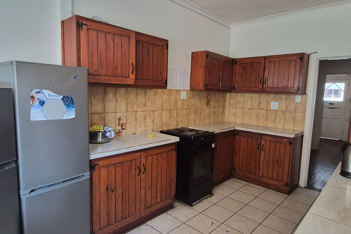 A functional kitchen featuring traditional wooden cabinetry, tiled backsplash, and tiled flooring, offering a dated aesthetic with potential for modern renovation.