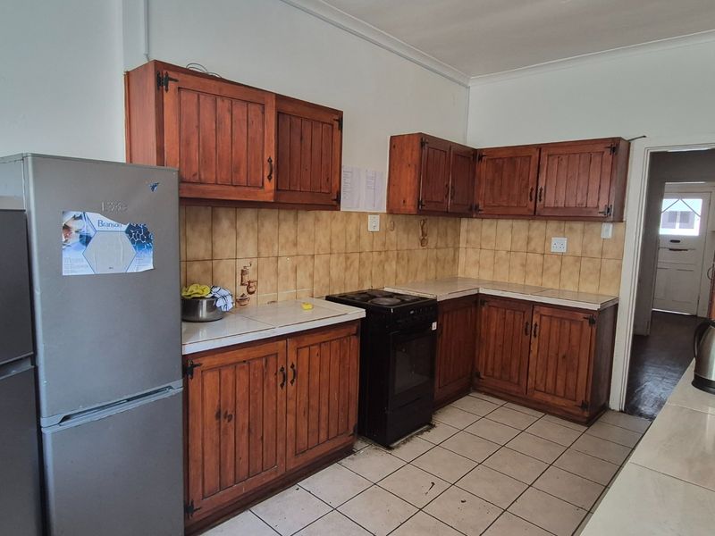 A functional kitchen featuring traditional wooden cabinetry, tiled backsplash, and tiled flooring, offering a dated aesthetic with potential for modern renovation.