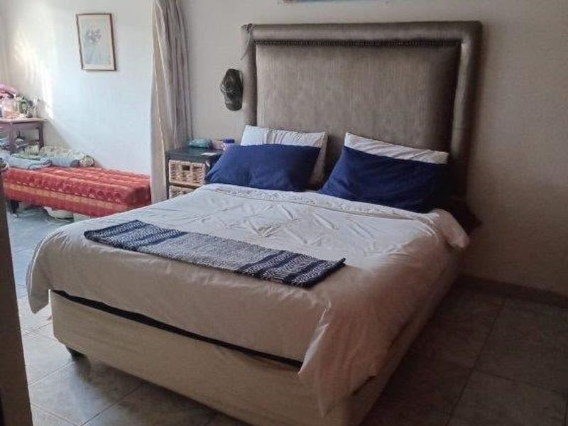 A bedroom featuring tiled flooring and recessed ceiling lighting, with an adjacent space visible through an open doorway.