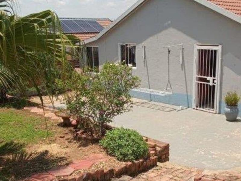 Rear exterior view of the house featuring a brick paved area, security gate, and wall-mounted washing line.