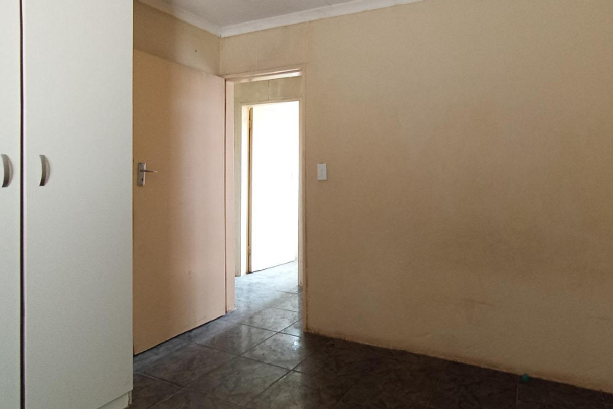An empty bedroom featuring tiled flooring and a built-in wardrobe, offering a blank canvas for potential updates and interior design.