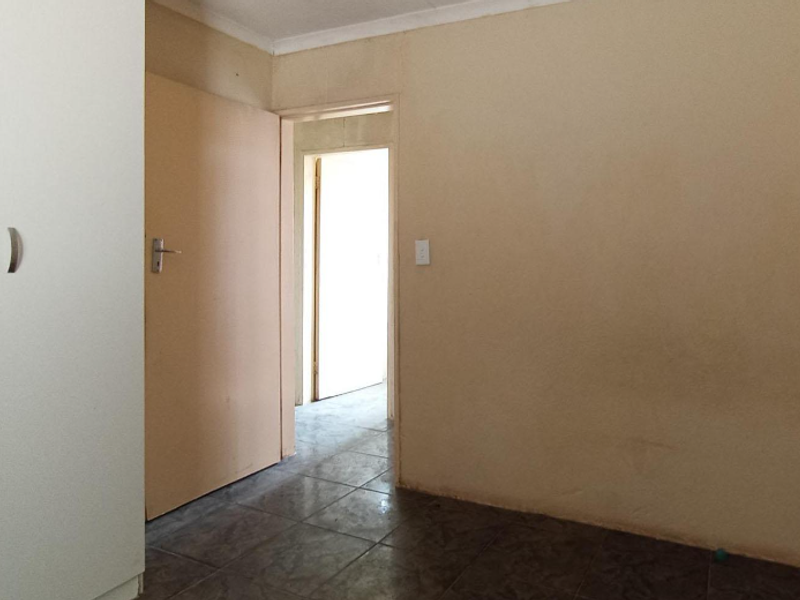 An empty bedroom featuring tiled flooring and a built-in wardrobe, offering a blank canvas for potential updates and interior design.