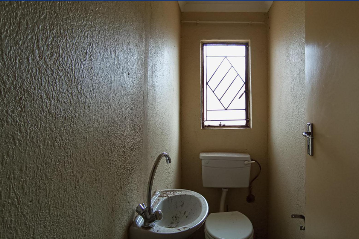 A small, dated bathroom featuring a basic toilet and washbasin, requiring cosmetic updates and refurbishment to improve its overall condition and appeal.