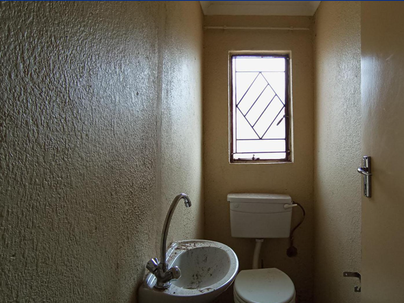 A small, dated bathroom featuring a basic toilet and washbasin, requiring cosmetic updates and refurbishment to improve its overall condition and appeal.