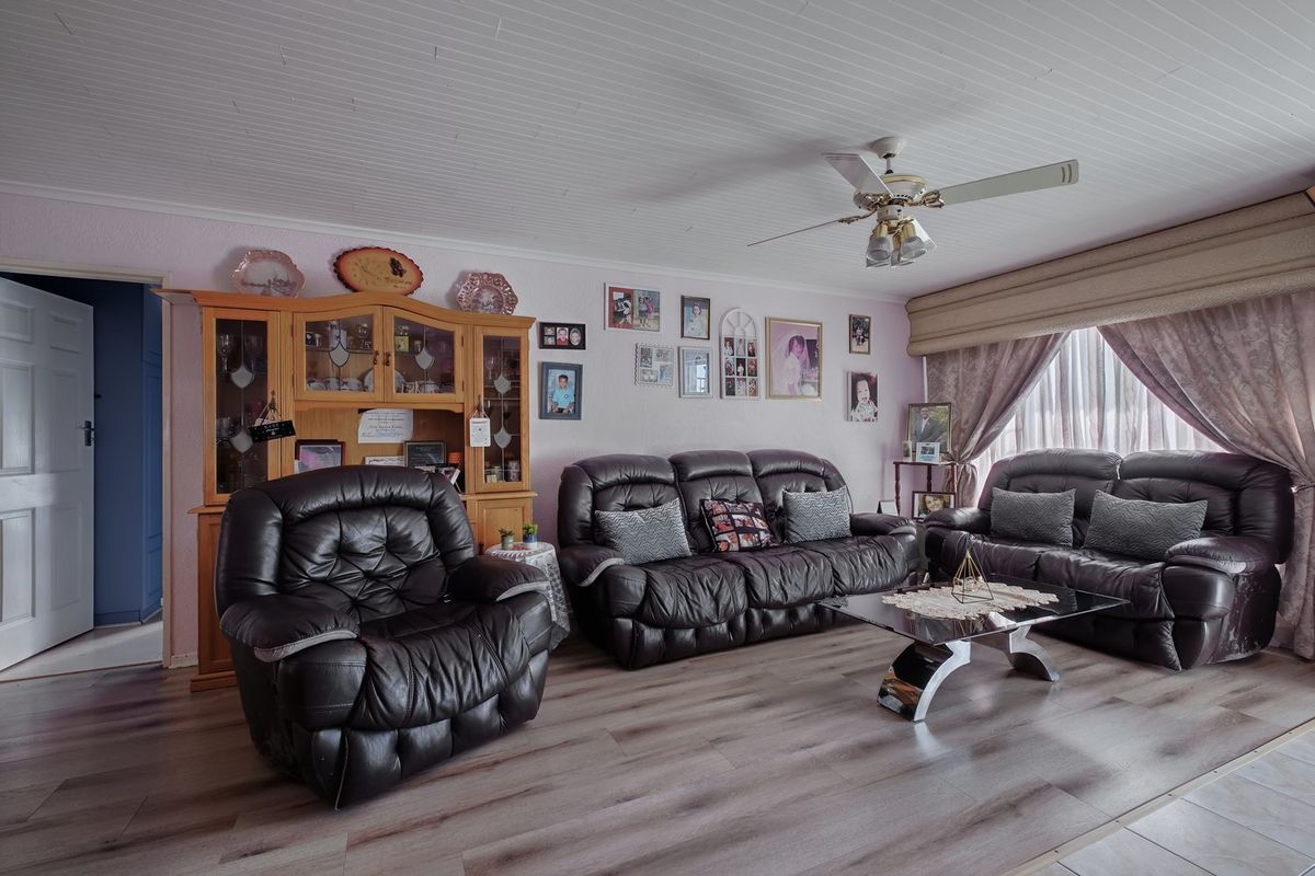 A comfortable living room featuring laminate flooring, a tongue and groove ceiling, and a central ceiling fan.