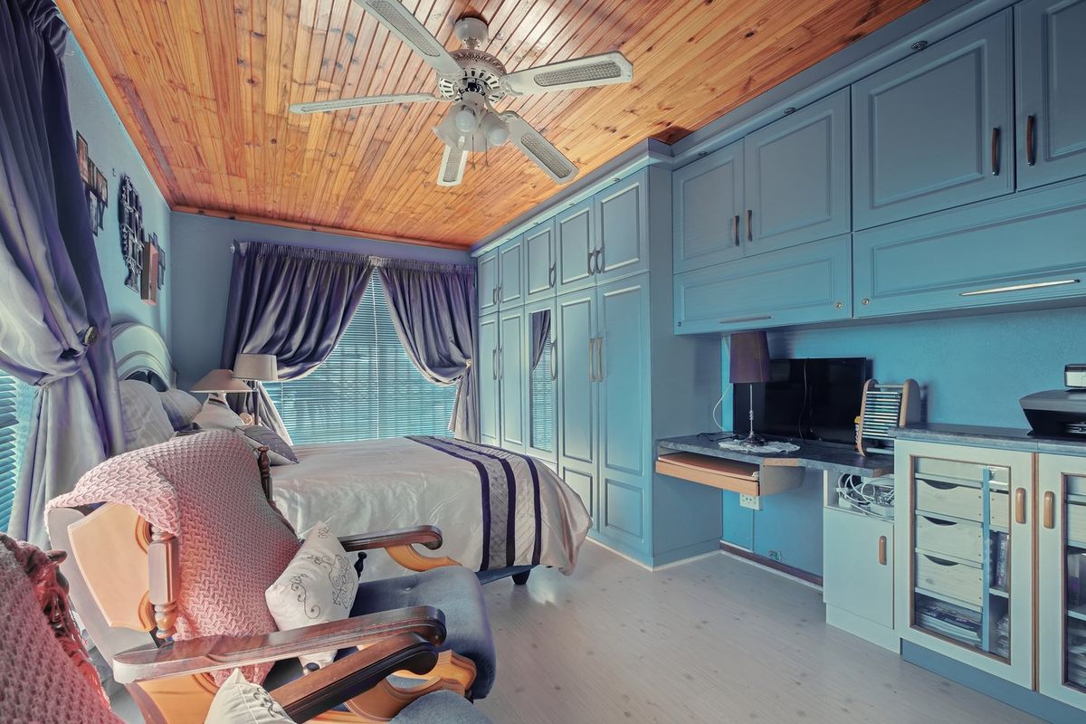 Bedroom featuring extensive built-in blue cabinetry, a built-in desk, and a natural timber ceiling with a central ceiling fan.
