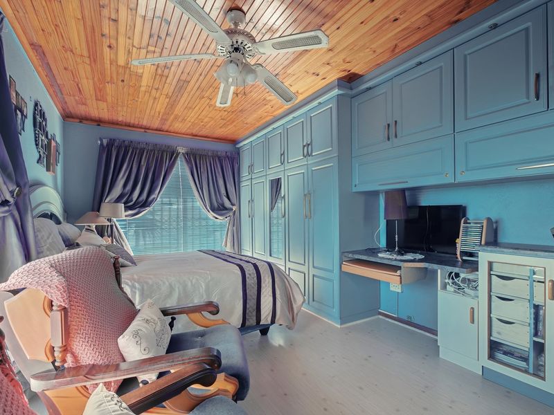 Bedroom featuring extensive built-in blue cabinetry, a built-in desk, and a natural timber ceiling with a central ceiling fan.