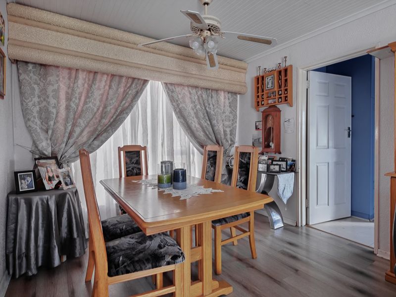 A dining room featuring laminate flooring, a ceiling fan, and a panelled ceiling, providing a functional space for meals.