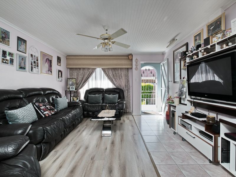 A living room featuring a combination of laminate and tiled flooring, a ceiling fan, and a tongue and groove ceiling with direct access to the exterior.
