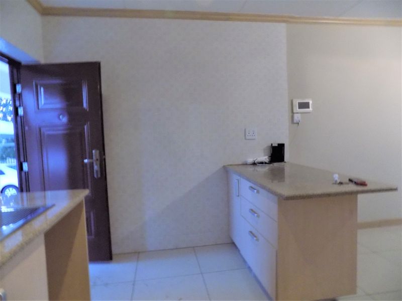 A functional kitchen area featuring built-in cabinetry, granite countertops, and tiled flooring, providing a clean and practical space for culinary activities.