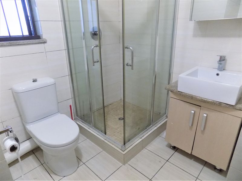 A functional bathroom featuring a glass shower enclosure, a modern vessel sink with a vanity cabinet, and a standard toilet.