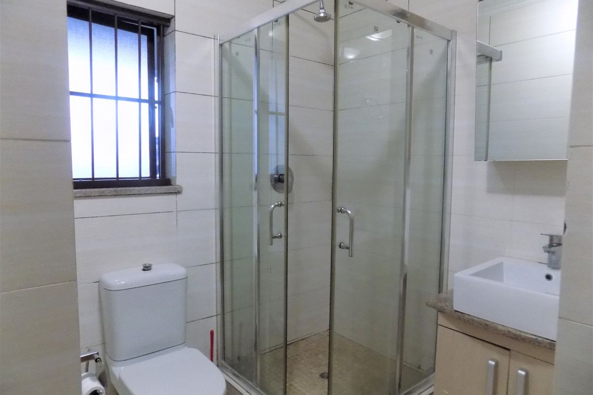 A functional bathroom featuring a glass shower enclosure, a modern vanity with a basin, and tiled wall finishes.