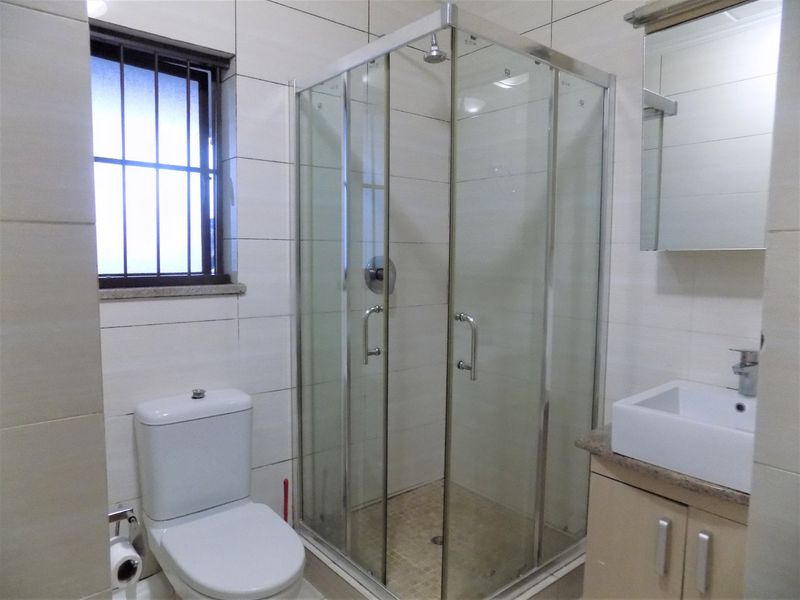 A functional bathroom featuring a glass shower enclosure, a modern vanity with a basin, and tiled wall finishes.
