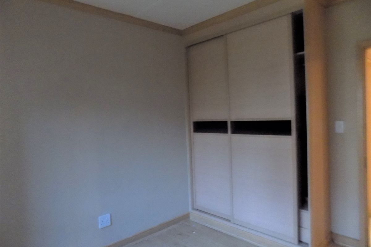 A bedroom featuring laminate flooring and a built-in sliding door wardrobe with a missing panel.
