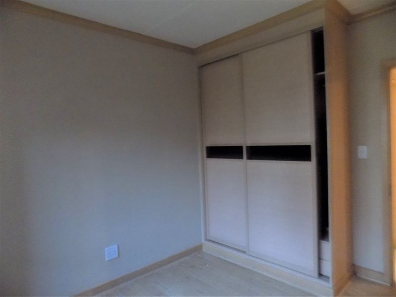 A bedroom featuring laminate flooring and a built-in sliding door wardrobe with a missing panel.
