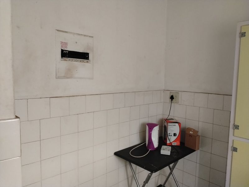 A utility area featuring a wall-mounted electrical distribution board and tiled splashback, requiring cosmetic attention to wall surfaces.