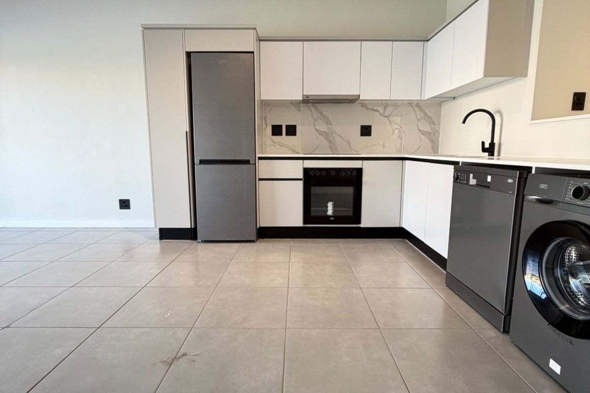 Modern, clean-lined kitchen featuring white cabinetry, marble-look splashback, built-in oven, extractor fan, and sleek tiled flooring in an open-plan layout.