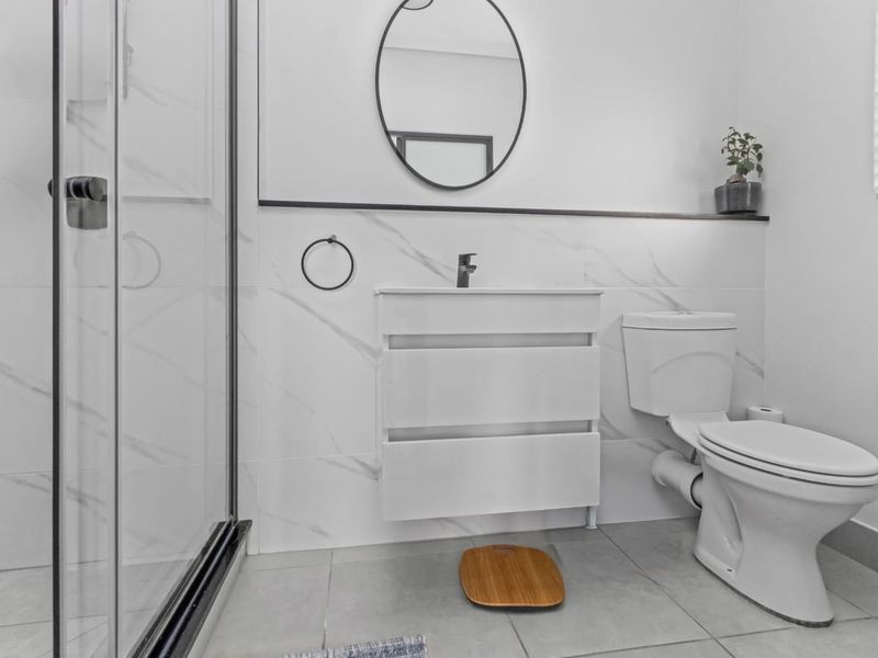 Modern bathroom featuring a glass shower enclosure, sleek vanity cabinet, and contemporary marble-look wall tiling.