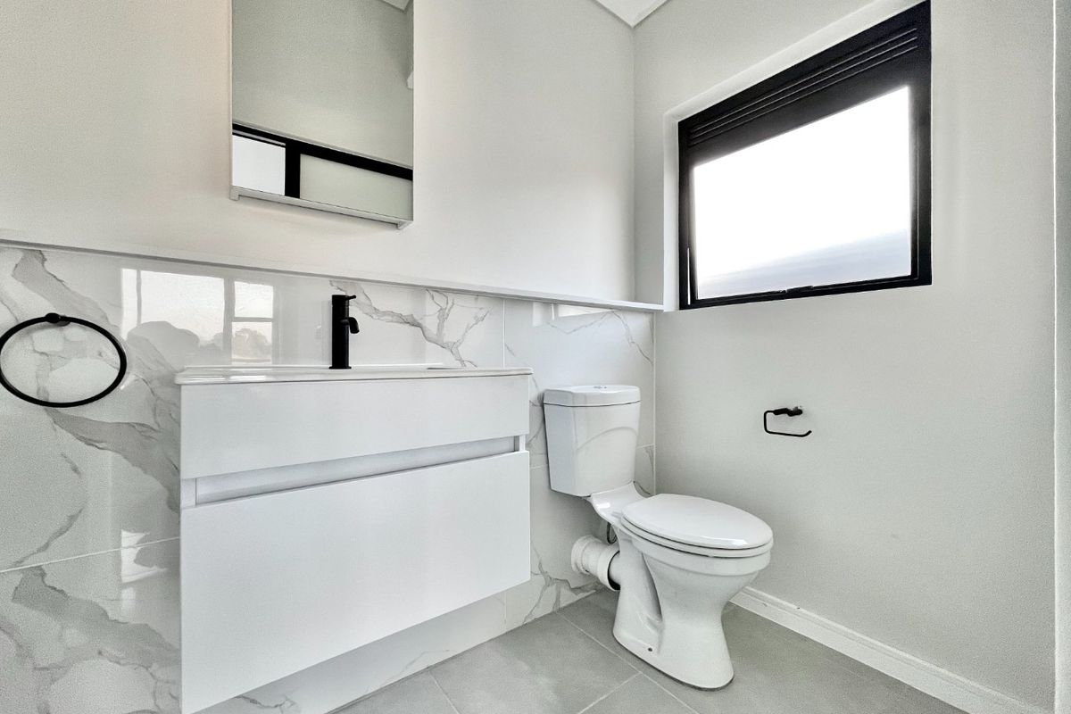 Modern bathroom featuring a wall-mounted vanity, marble-look tiled splashback, black fixtures, and a clean, contemporary aesthetic.