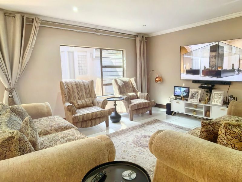 A well-maintained living room featuring tiled flooring, recessed lighting, and a sliding door with a security gate providing access to the exterior.