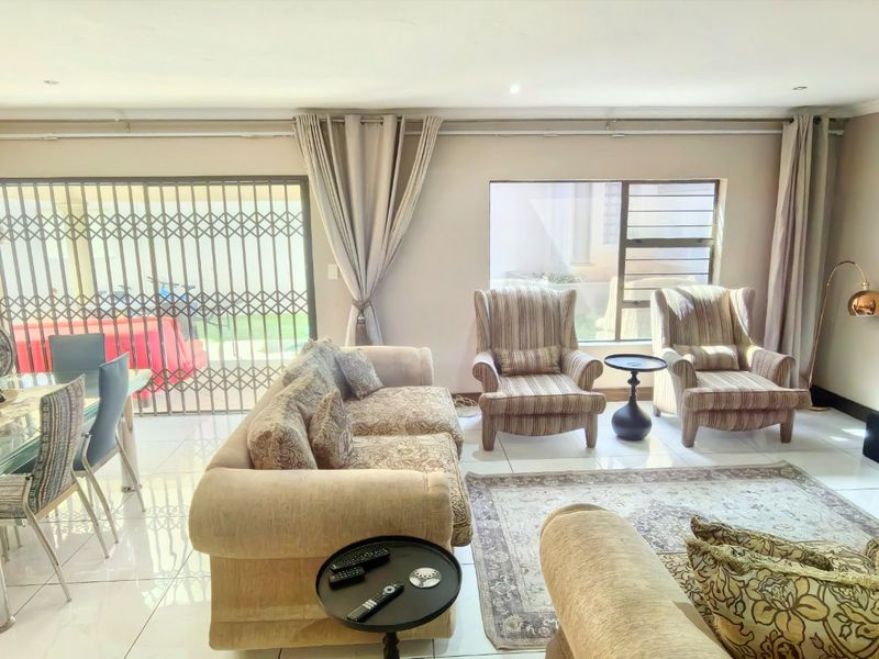 Spacious open-plan living and dining area featuring polished tiled flooring, large windows, and direct access to the outdoor patio through a sliding glass door.