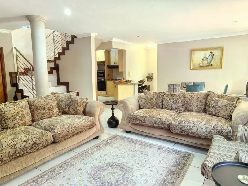 Spacious open-plan living area featuring tiled flooring, a central structural column, and an integrated kitchen with built-in cabinetry and appliances.