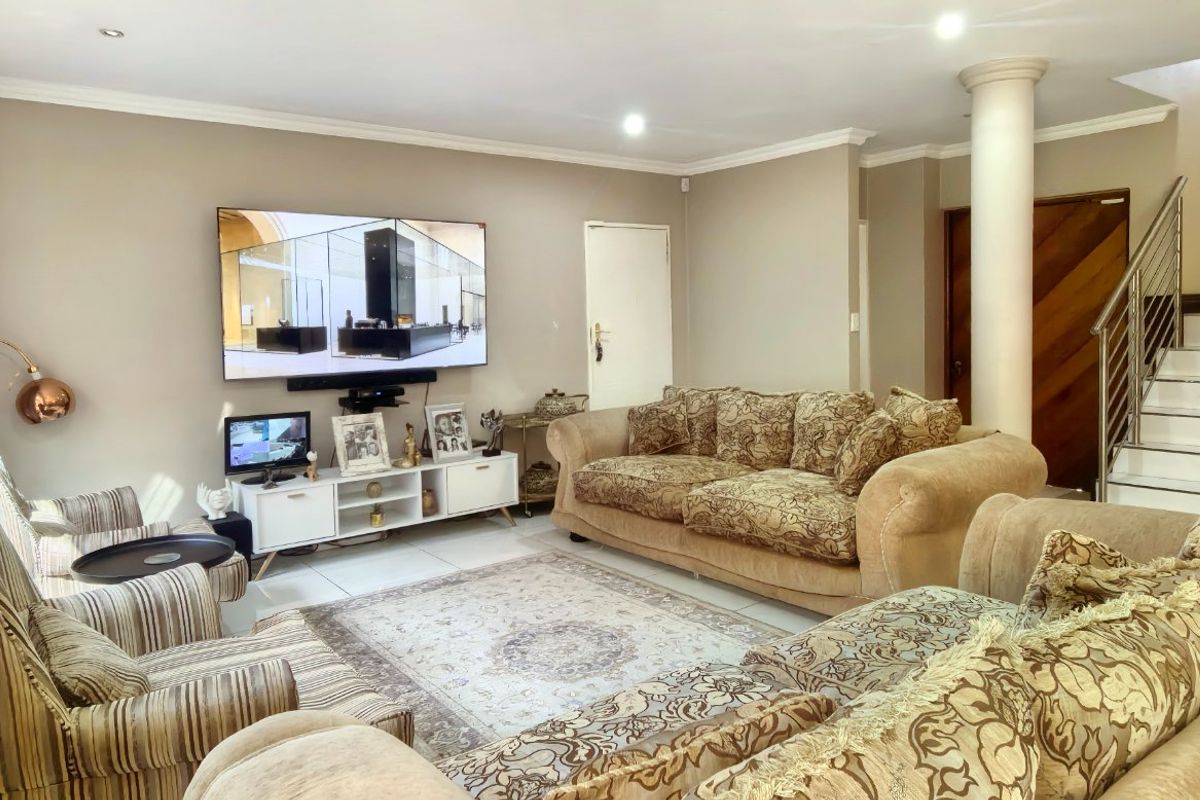 Spacious living room featuring tiled flooring, recessed lighting, and a staircase with a modern stainless steel balustrade.
