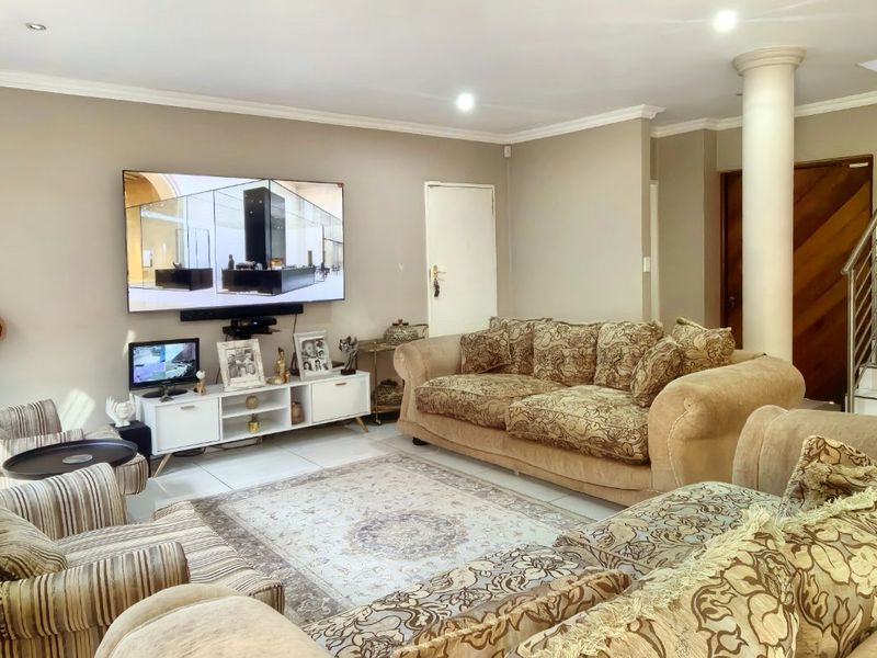 Spacious living room featuring tiled flooring, recessed lighting, and a staircase with a modern stainless steel balustrade.