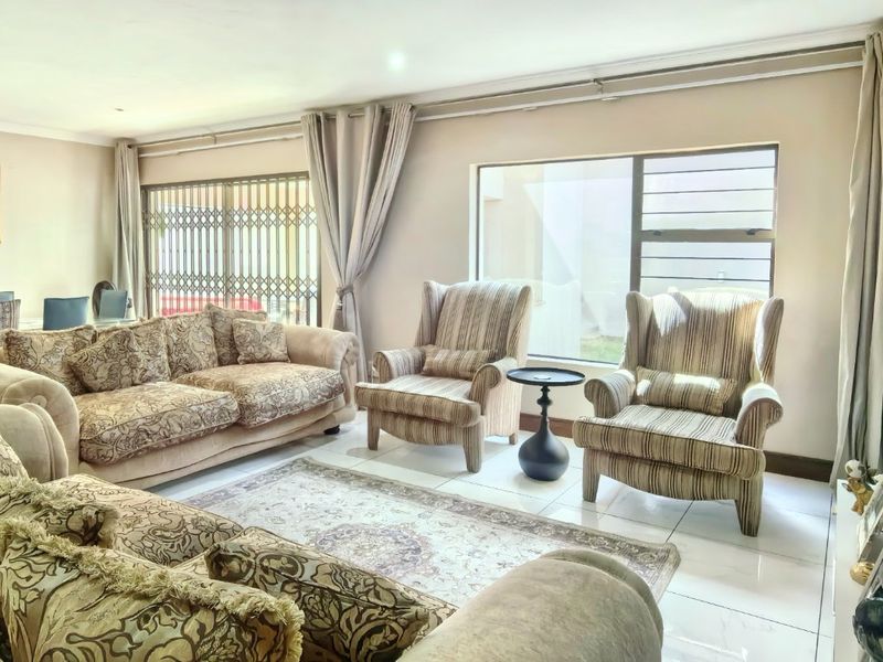 Spacious open-plan living and dining area featuring large windows, sliding glass doors, and neutral tiled flooring, offering a bright and versatile layout.