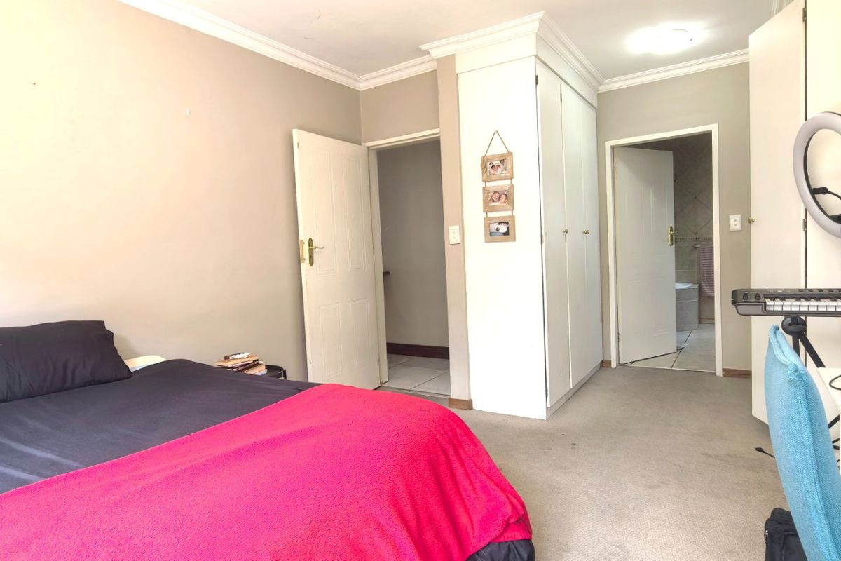 A functional bedroom featuring built-in cupboards, carpeted flooring, and direct access to an en-suite bathroom.
