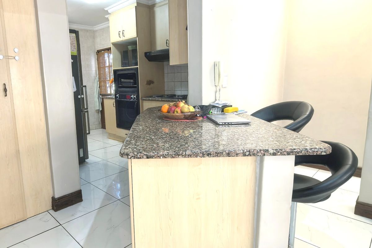 A functional kitchen featuring granite countertops, built-in oven, extractor fan, and tiled flooring with light wood-finish cabinetry.