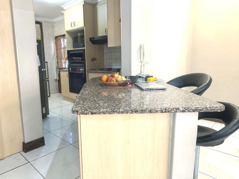 A functional kitchen featuring granite countertops, built-in oven, extractor fan, and tiled flooring with light wood-finish cabinetry.