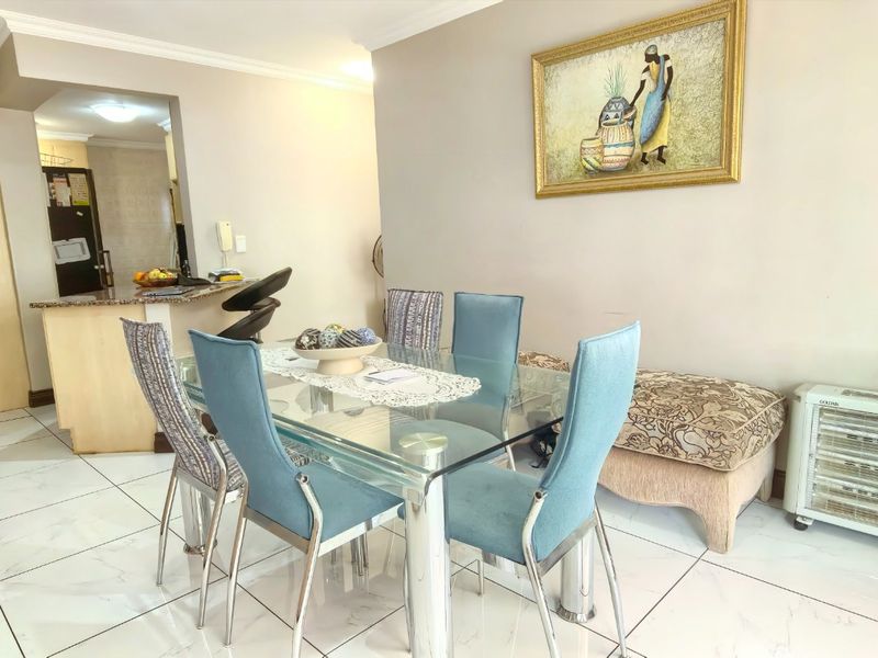 Open plan dining area featuring tiled flooring, a breakfast counter, and access to the staircase, creating a functional living space.
