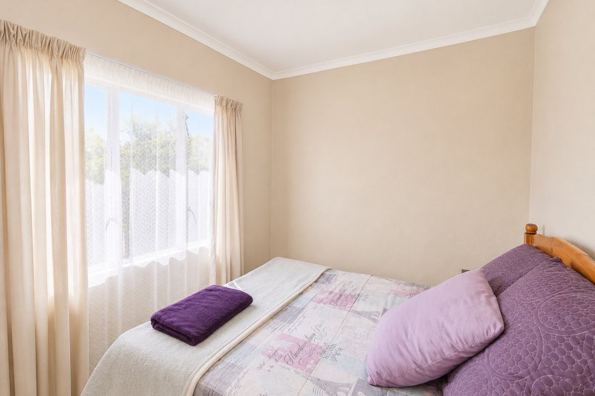 A neutrally painted bedroom featuring a window with curtains and coving detail.