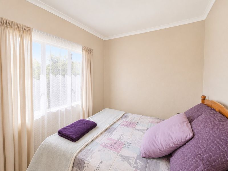 A neutrally painted bedroom featuring a window with curtains and coving detail.