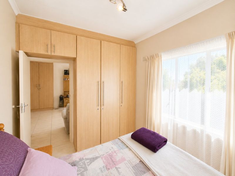A well-lit bedroom featuring extensive built-in wooden cabinetry and a large window, providing ample storage and natural light.