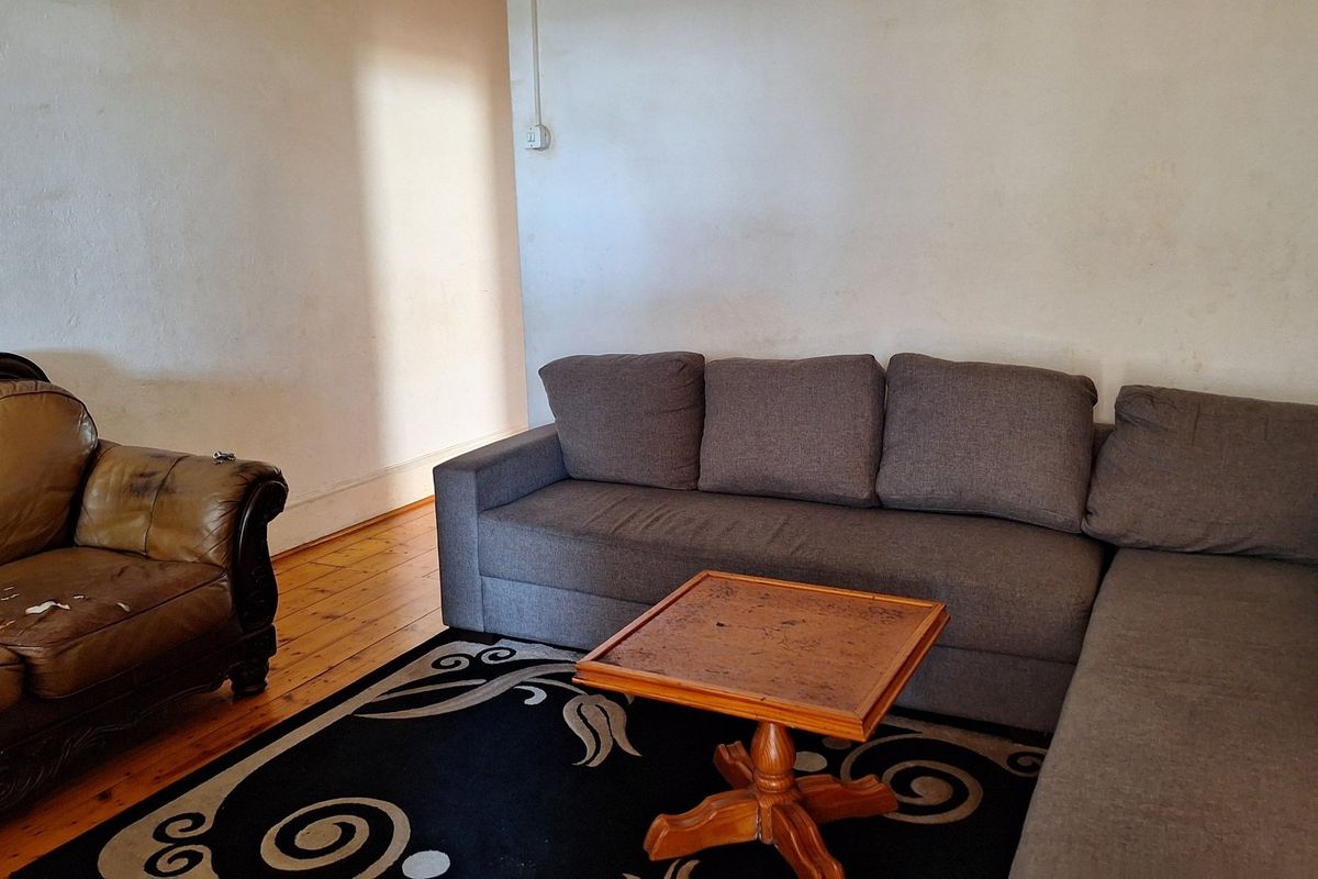 A living room featuring original timber flooring and plain wall finishes, offering a blank canvas for potential interior updates and modernization.