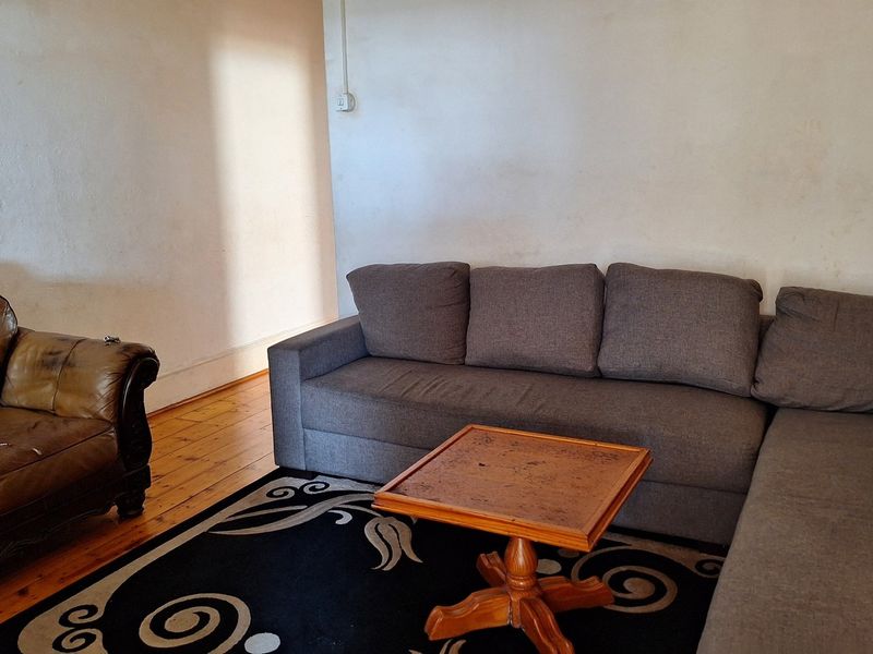 A living room featuring original timber flooring and plain wall finishes, offering a blank canvas for potential interior updates and modernization.