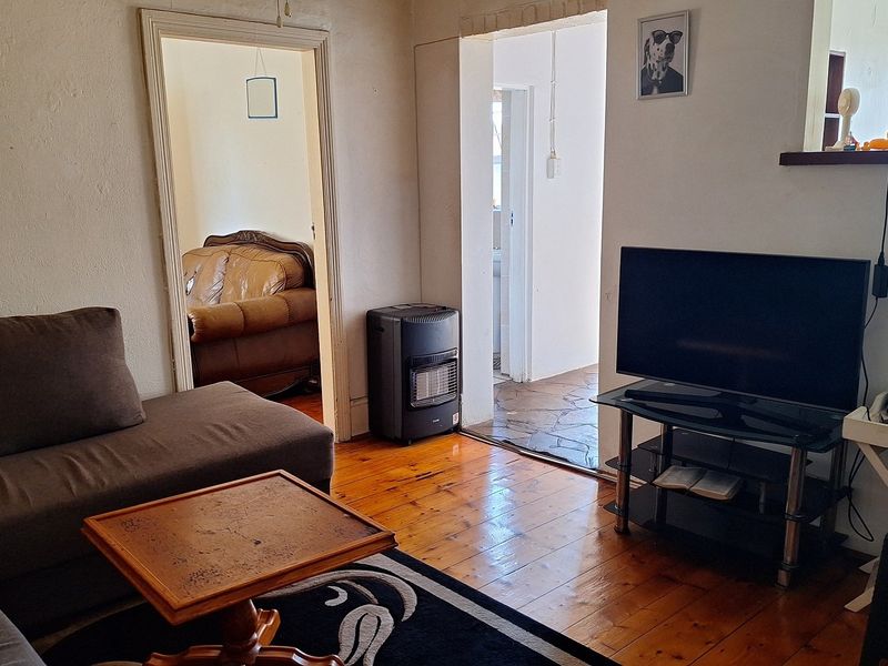 Living room featuring polished timber flooring and an open archway leading to adjacent rooms, providing a functional and connected living space.
