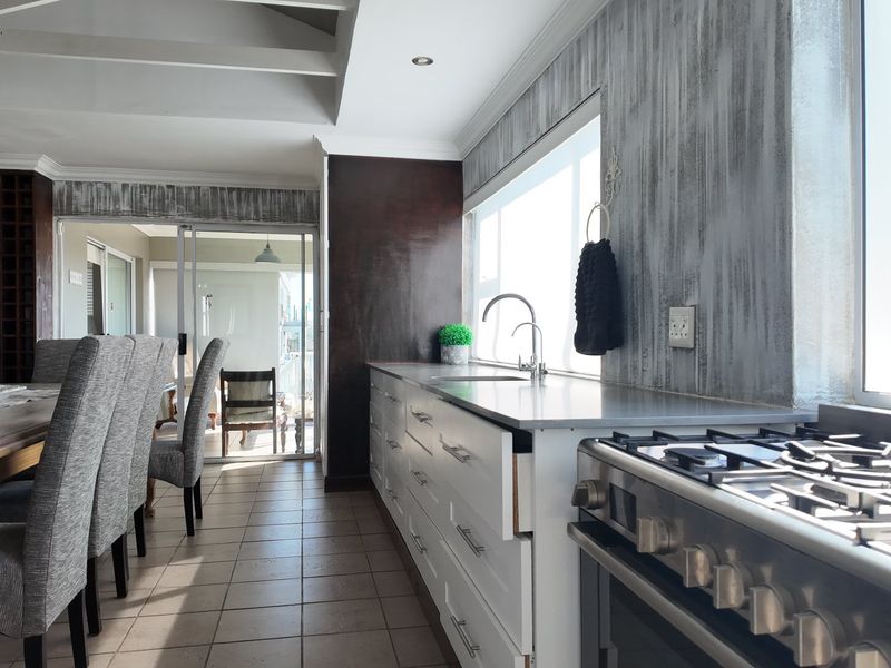 Open plan kitchen and dining area featuring a gas stove, stainless steel countertops, and direct access to an outdoor patio through sliding glass doors.