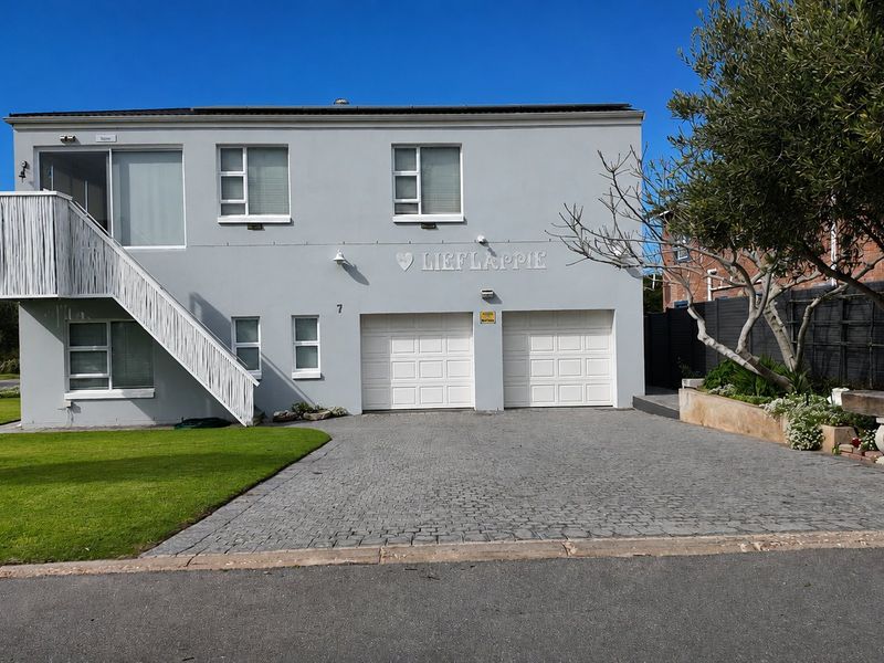 Front elevation of a two-story house featuring a double garage, paved driveway, and an external staircase leading to an upper-level balcony.