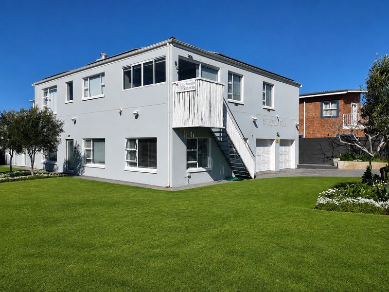 A well-maintained two-story residential property featuring a double garage, external staircase access to the upper level, and a neatly landscaped front garden.