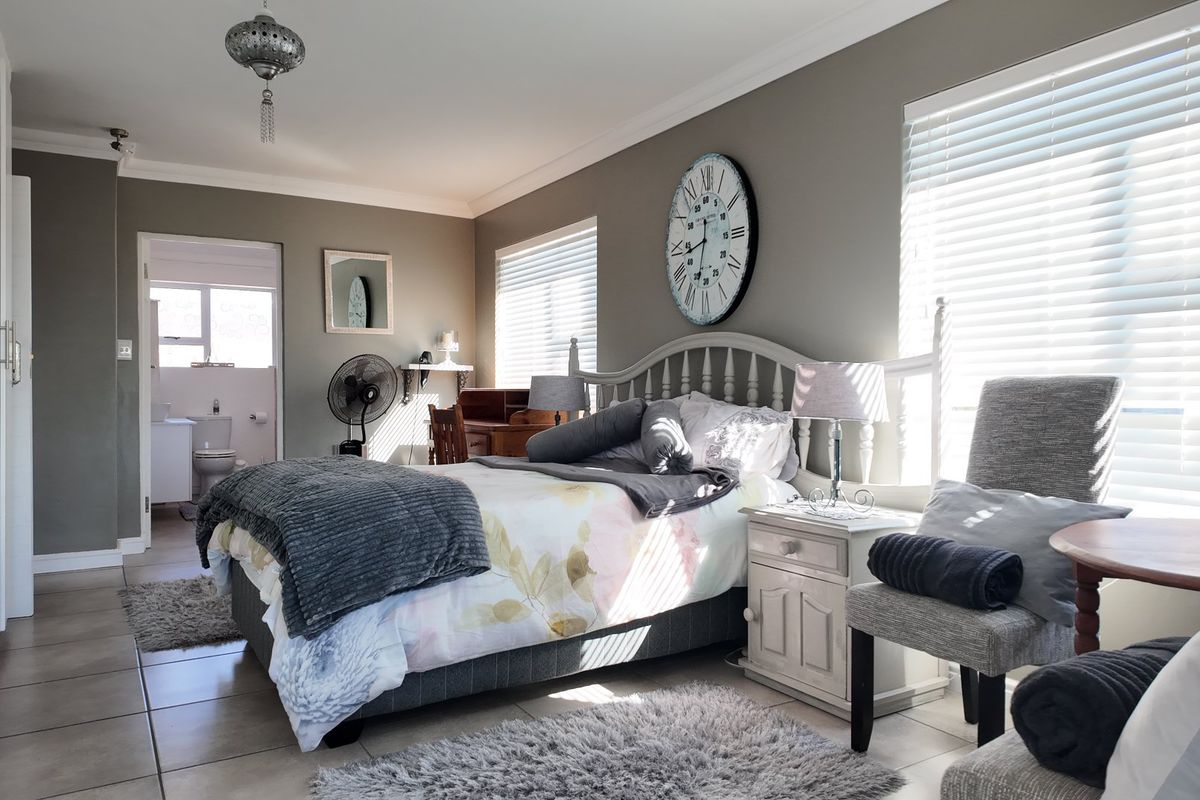 Spacious bedroom featuring tiled flooring, built-in cupboards, and an en-suite bathroom, offering a comfortable and functional living space.