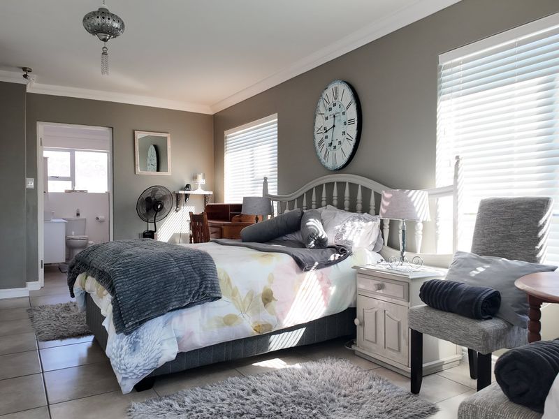 Spacious bedroom featuring tiled flooring, built-in cupboards, and an en-suite bathroom, offering a comfortable and functional living space.